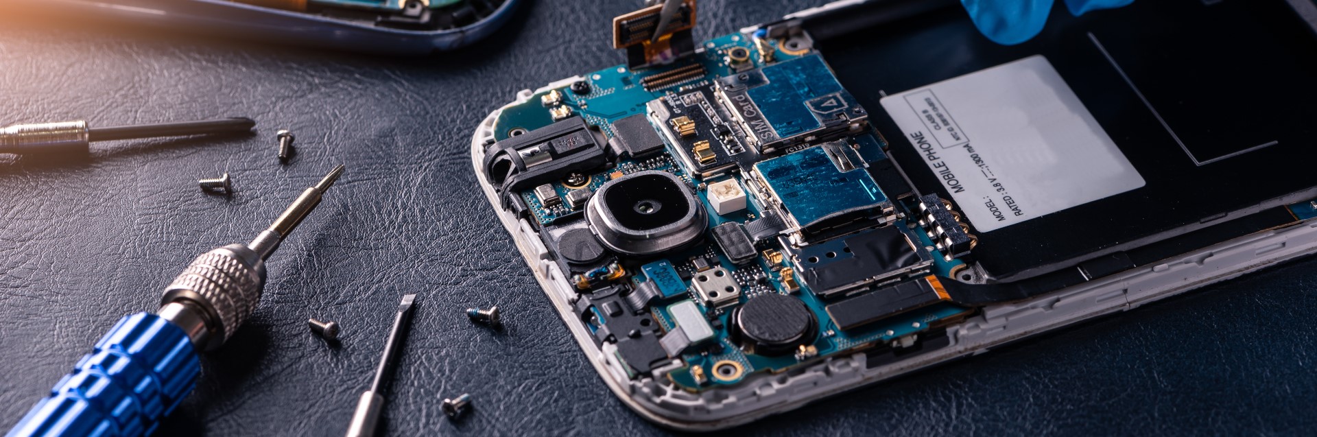 Tools and screws next to mobile phone being repaired at JD Technology Services